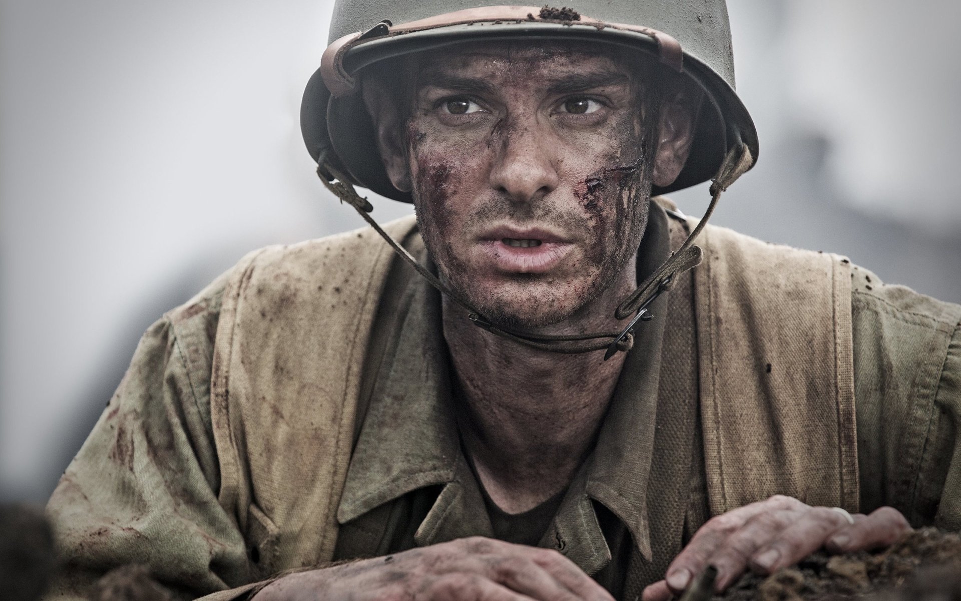 A dramatic HD wallpaper featuring Andrew Garfield as a soldier in World War II, portraying the intense atmosphere of the film Hacksaw Ridge.