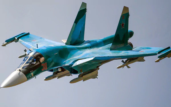 HD PC desktop wallpaper of a Sukhoi Su-34 military warplane aircraft: twin-seat jet fighter in blue camouflage banking with missile-laden wings against a clear sky.