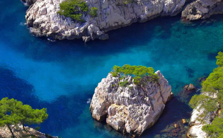 2K Quad HD PC desktop wallpaper/background: aerial view of Marseille, France coastline — turquoise sea around rocky islets topped with pines, vivid coastal nature.