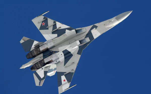 A Sukhoi Su-35 jet fighter soars gracefully through a clear blue sky, showcasing its sleek design and military camouflage in this stunning 4K Ultra HD wallpaper.