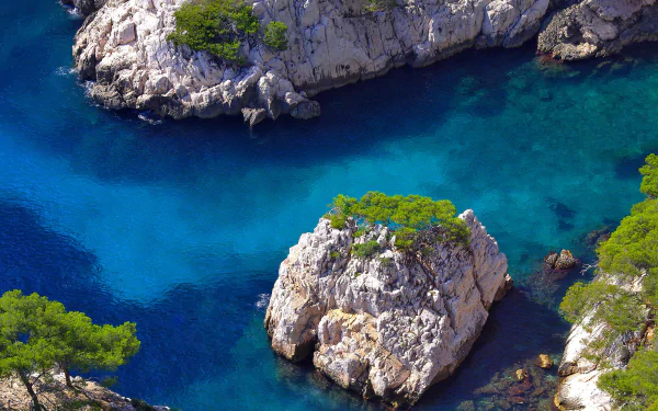 2K Quad HD PC desktop wallpaper/background: aerial view of Marseille, France coastline — turquoise sea around rocky islets topped with pines, vivid coastal nature.