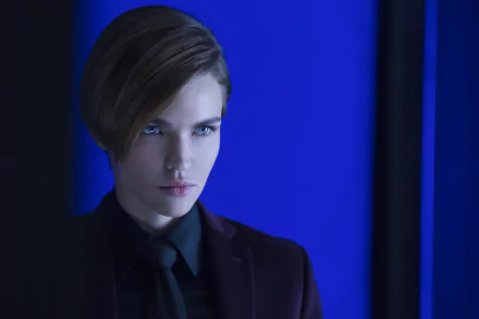 HD desktop wallpaper featuring Ruby Rose from the movie John Wick: Chapter 2 standing against a blue background, wearing a dark suit and tie.