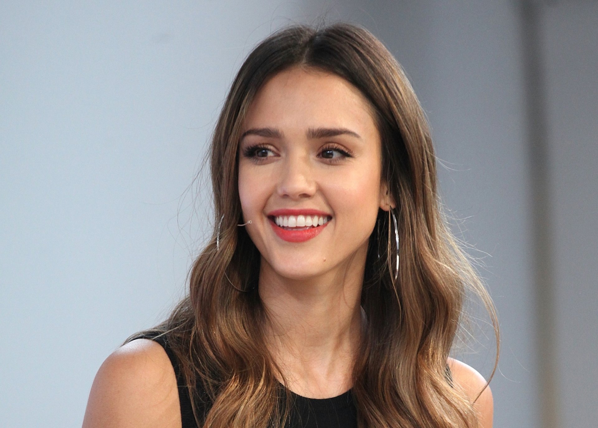 HD desktop wallpaper featuring American actress Jessica Alba with brunette hair, brown eyes, and a warm smile.