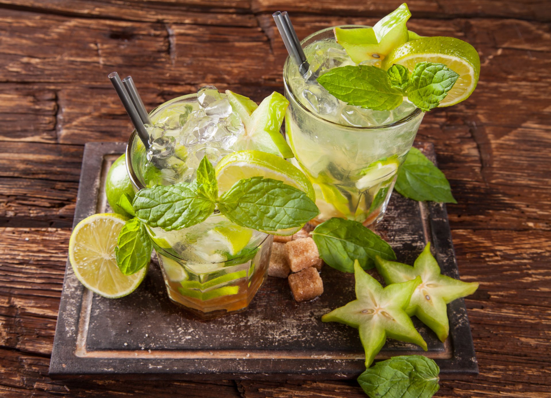A vibrant 4K Ultra HD desktop wallpaper featuring two refreshing sugar-coated fruit cocktails garnished with lime, starfruit slices, and fresh mint in clear glasses.
