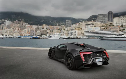 HD PC desktop wallpaper featuring a sleek black Lykan HyperSport parked by a waterfront with a cityscape and cloudy sky in the background.