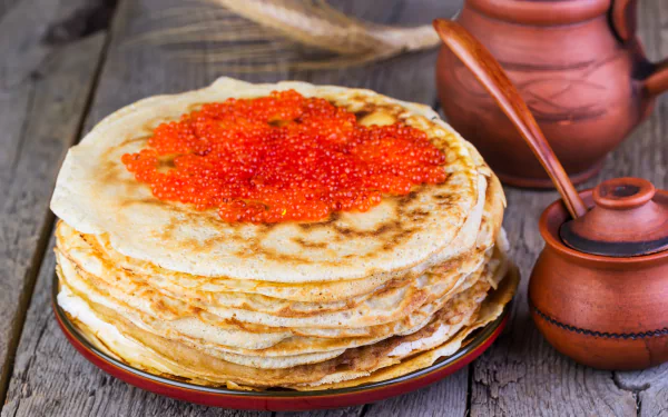 5K Ultra HD PC desktop wallpaper of stacked crêpes topped with bright red caviar on a rustic wooden table, accompanied by ceramic jars and a wooden spoon.