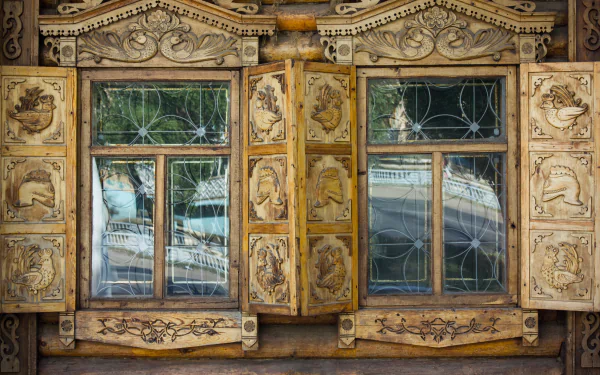 Ornate wooden window shutters with intricate carvings on a traditional man-made house in Orenburg, captured in sharp 4K Ultra HD detail.