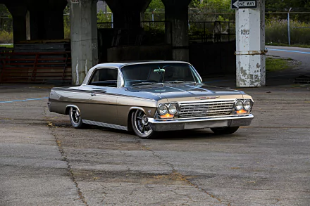 Low-slung silver Chevrolet Impala muscle car hot rod vehicle with chrome trim and custom wheels parked beneath a concrete overpass — HD PC desktop wallpaper background.