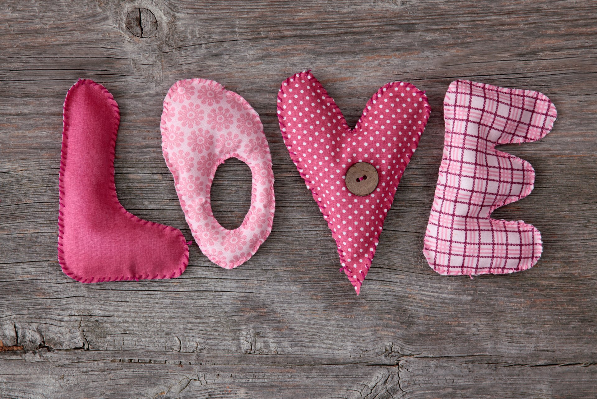 HD desktop wallpaper featuring the word LOVE crafted from colorful, patterned fabric letters against a rustic wooden background, radiating an artistic and affectionate vibe.