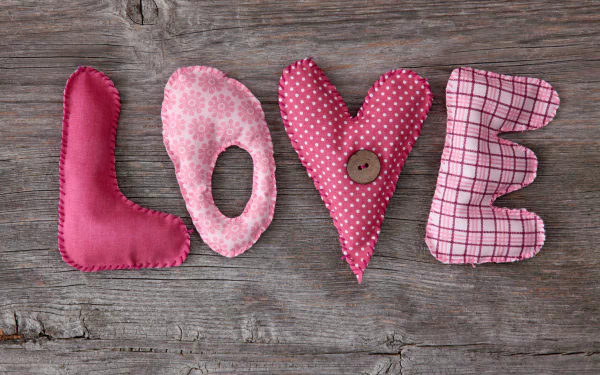 HD desktop wallpaper featuring the word LOVE crafted from colorful, patterned fabric letters against a rustic wooden background, radiating an artistic and affectionate vibe.