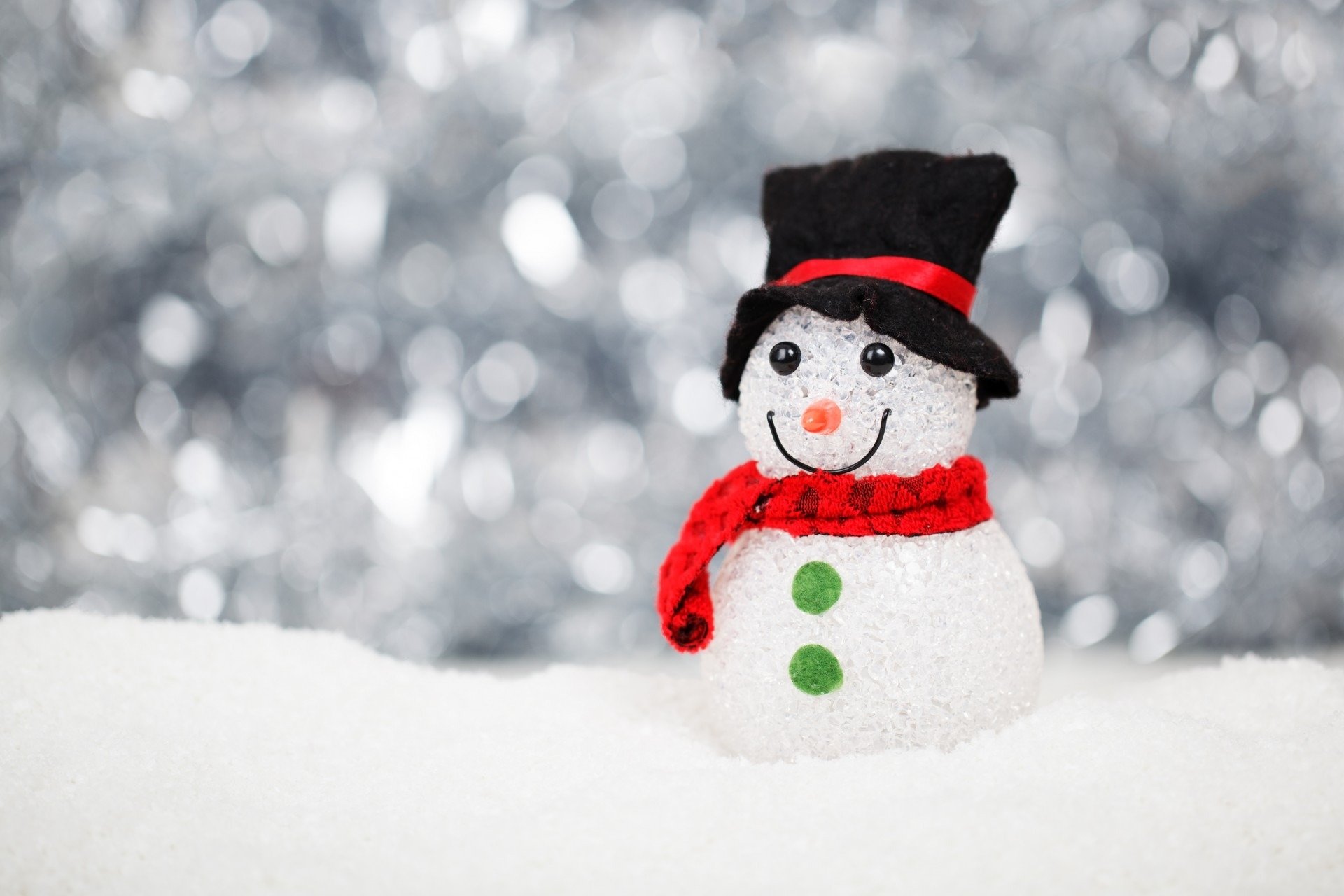 Artistic HD desktop wallpaper featuring a cheerful snowman with a black top hat and red scarf against a sparkling, blurred snowy background.