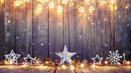 A festive HD desktop wallpaper showing a wooden background adorned with glowing lights, stars, and snowflakes, capturing a warm holiday and Christmas atmosphere.