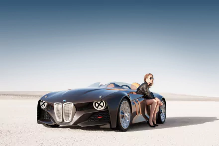 HD desktop wallpaper featuring a sleek black BMW 328 Hommage with a woman in sunglasses sitting beside the vehicle on a flat, open landscape under a clear sky.