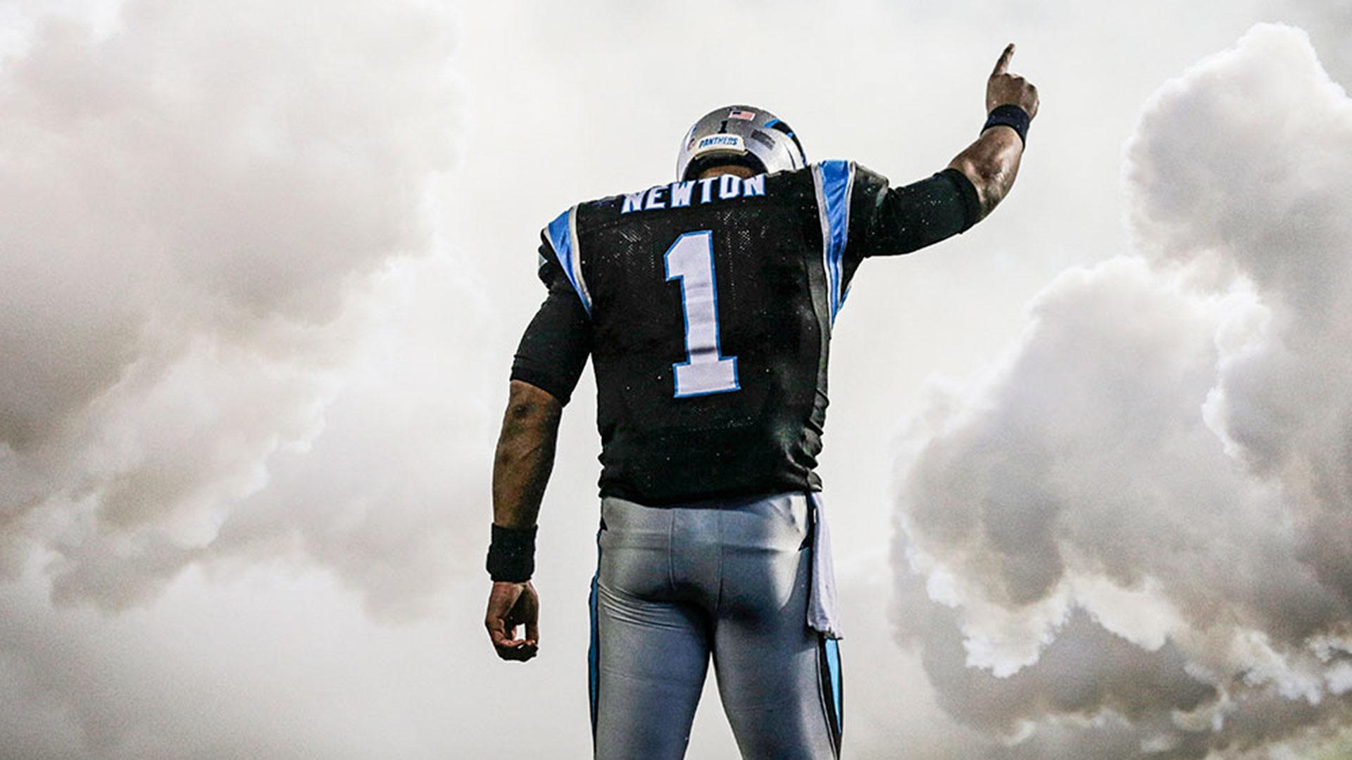 HD desktop wallpaper of Cam Newton with his back turned, jersey number 1 visible, pointing upwards against a cloudy sky background.