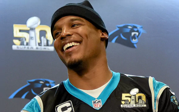 HD wallpaper of Cam Newton smiling at an event, wearing a Carolina Panthers jersey, with a Super Bowl 50 logo in the background.