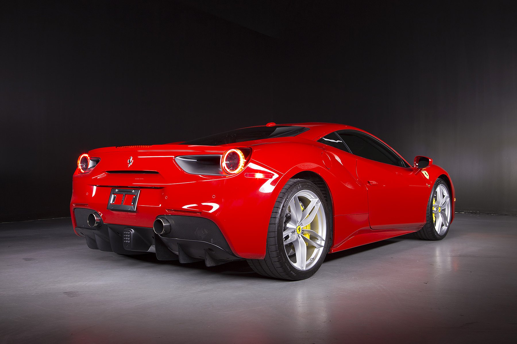 Red Ferrari 488 GTB supercar, rear three-quarter view on a dark studio floor — HD PC desktop wallpaper and vehicle background.