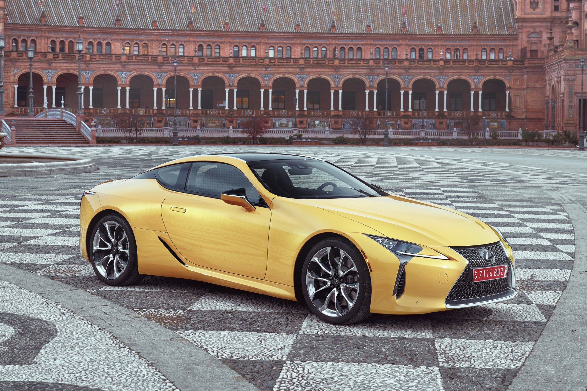 Yellow Lexus LC 500 grand tourer parked on a patterned plaza before an ornate brick arcade — 4K Ultra HD PC desktop wallpaper/background.