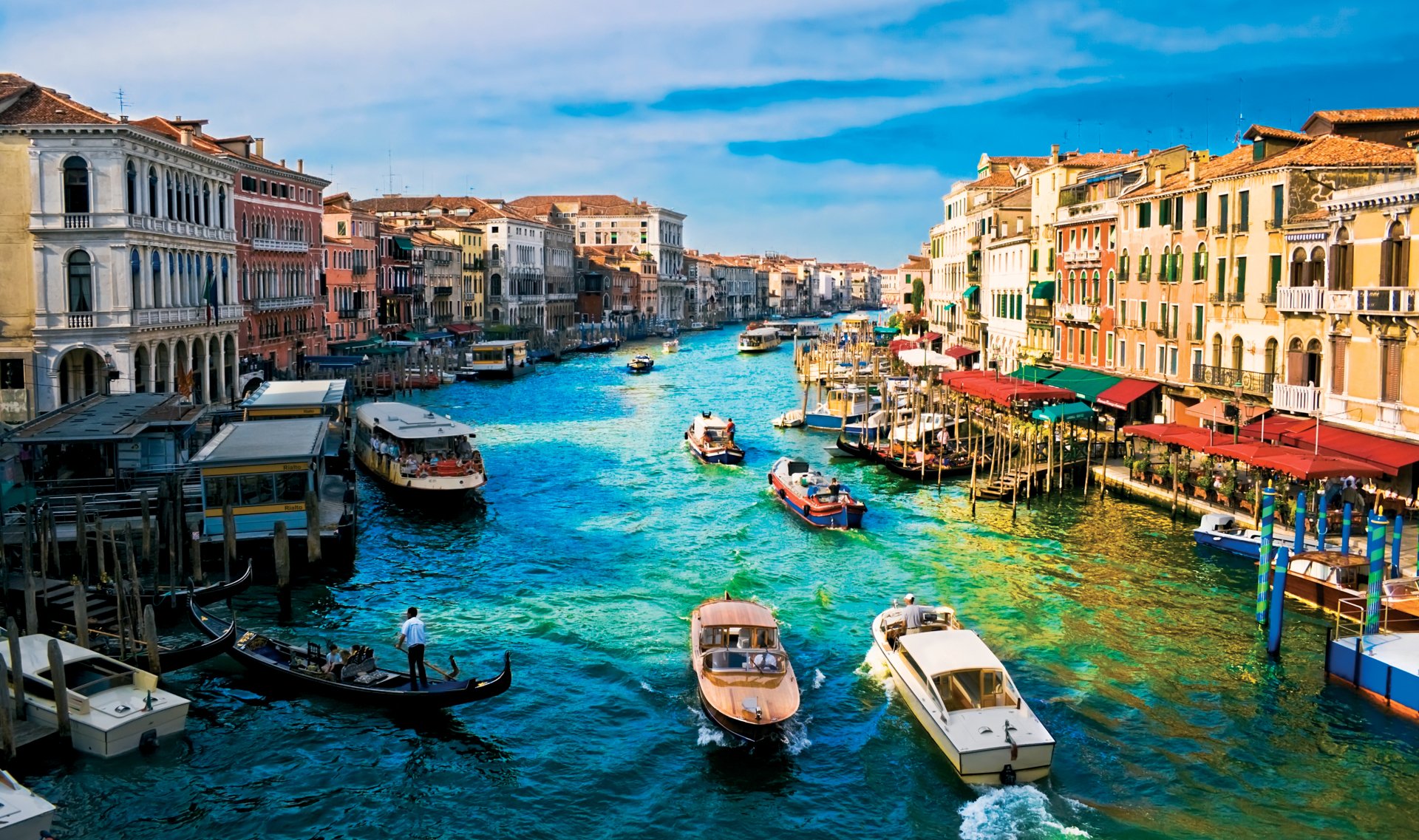 HD desktop wallpaper of the Grand Canal in Venice, Italy, featuring boats navigating through the vibrant cityscape lined with historical buildings.