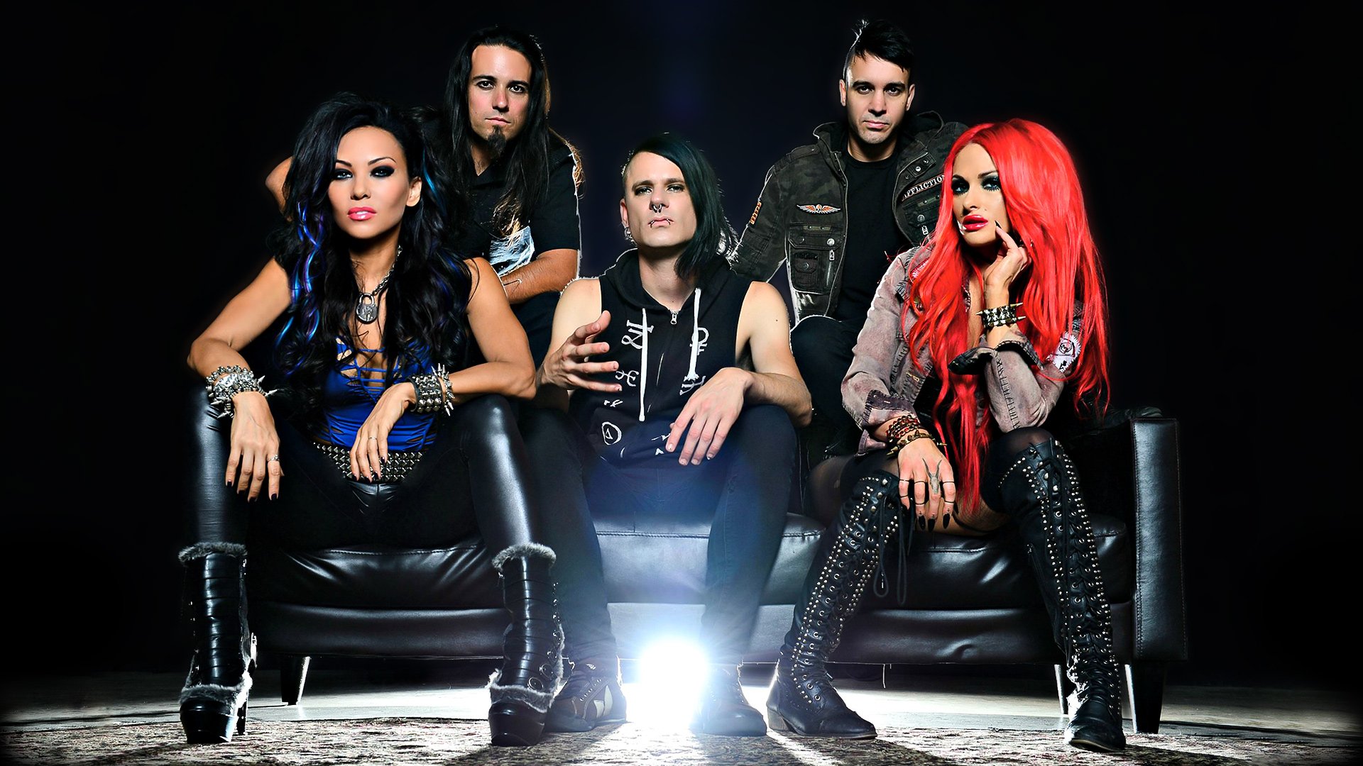HD desktop wallpaper featuring the death metal band Butcher Babies in edgy heavy metal attire, seated on a black sofa against a dark background.