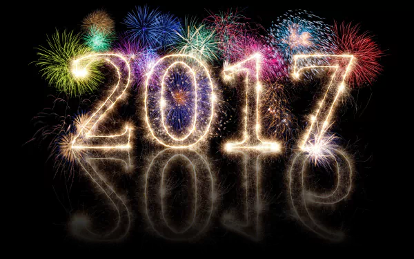 Bright fireworks illuminate the night sky above sparkling 2017 numbers, celebrating the New Year holiday in this vibrant 8K Ultra HD desktop wallpaper.