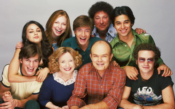 HD PC desktop wallpaper of a smiling nine-person group photo from the TV series That '70s Show, characters posed close together against a simple light backdrop.