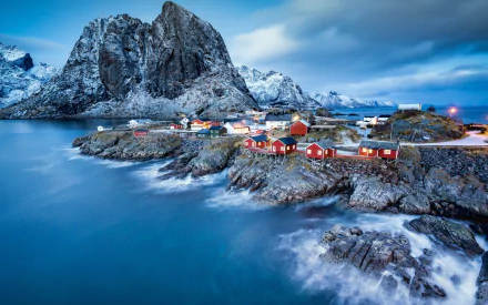 HD desktop wallpaper of the picturesque village of Reine in Lofoten, Norway, featuring vibrant red houses by the fjord with towering snow-capped mountains in the background.