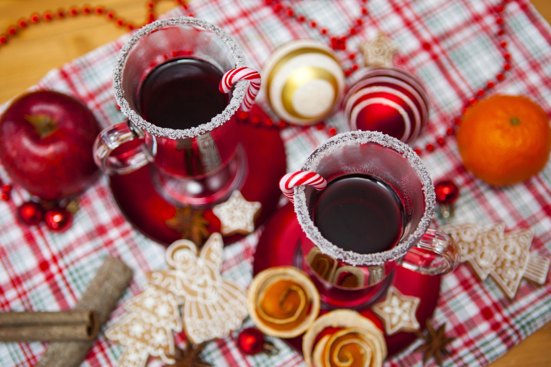 4K Ultra HD PC desktop wallpaper: festive Christmas scene with two sugar-rimmed glasses of mulled wine garnished with candy canes, surrounded by cookies, ornaments and fruit.