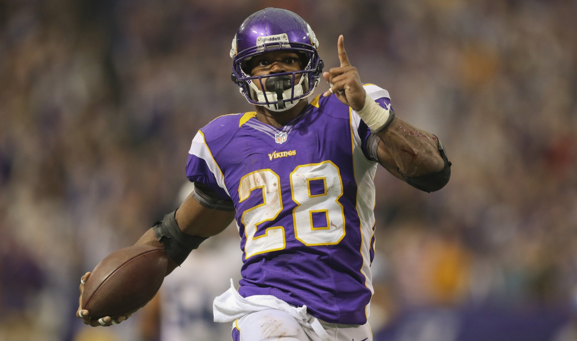 HD desktop wallpaper featuring a dynamic action shot of a football player in a purple jersey with the number 28, mid-game.