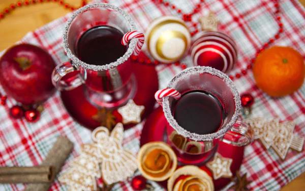 4K Ultra HD PC desktop wallpaper: festive Christmas scene with two sugar-rimmed glasses of mulled wine garnished with candy canes, surrounded by cookies, ornaments and fruit.