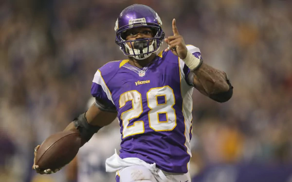 HD desktop wallpaper featuring a dynamic action shot of a football player in a purple jersey with the number 28, mid-game.