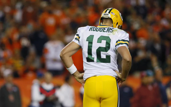 HD wallpaper of Aaron Rodgers, number 12, from behind on the football field, with a crowd in the background.