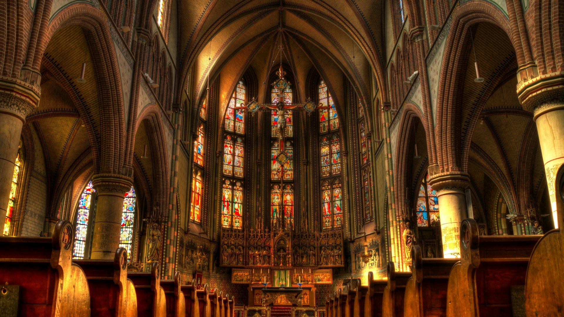 St Joseph's Cathedral interior, Groningen — illuminated Gothic nave with stained-glass windows and central Christian cross; religious church/cathedral presented as 4K Ultra HD PC desktop wallpaper.