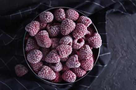 HD desktop wallpaper featuring a close-up of fresh raspberries in a bowl, with a dark, textured background adding contrast to the vibrant fruit.