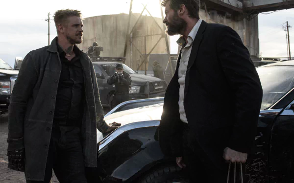 HD wallpaper featuring a scene from the movie Logan with Hugh Jackman engaged in a tense standoff with another character, set in an industrial environment with vehicles and armed personnel in the background.