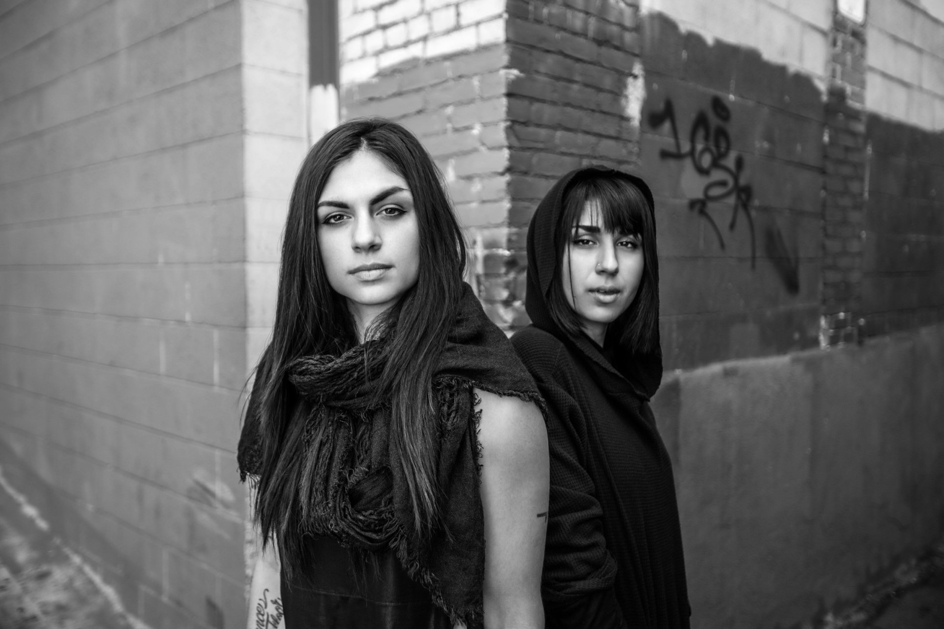 Black and white HD PC desktop wallpaper featuring music duo Krewella standing against an urban brick wall with graffiti in the background.