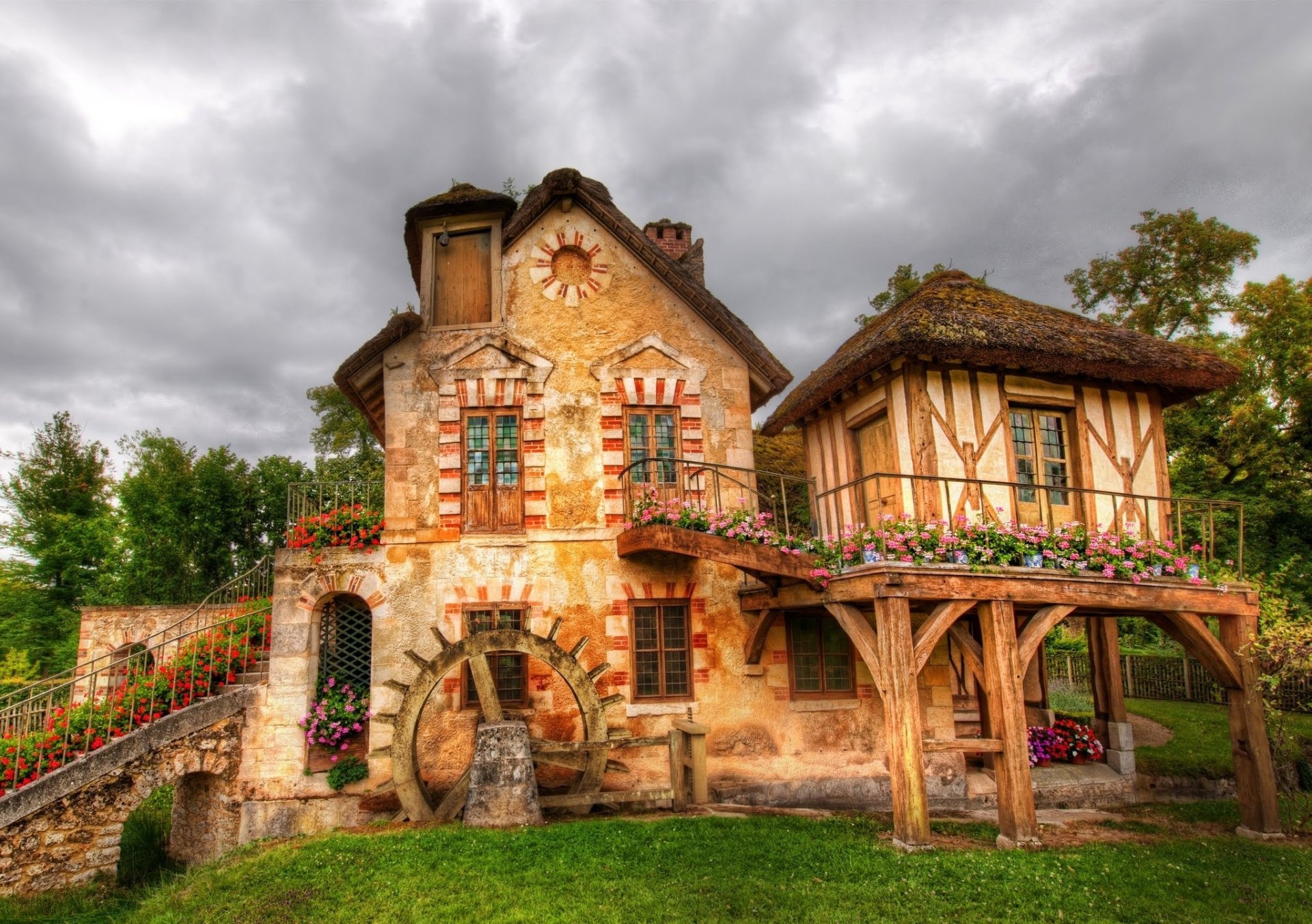 HD wallpaper of a charming country house adorned with flowers, blending natural beauty and man-made architecture under a cloudy sky.