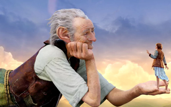 A HD wallpaper from the movie The BFG (2016) showing the giant holding a young girl in his hand against a scenic sky backdrop.