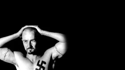 Black and white HD wallpaper featuring Ed Norton from the movie American History X, showing him shirtless with a prominent swastika tattoo on his chest against a stark black background.