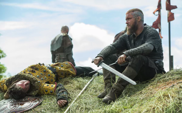 HD PC desktop wallpaper featuring a scene from the TV show Vikings (2013) with a warrior sitting beside a fallen opponent on a grassy hill under a cloudy sky.