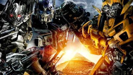 HD wallpaper featuring characters from the movie Transformers: Revenge of the Fallen, with Optimus Prime, Bumblebee, and Megatron standing before a pyramid under a dramatic sky.