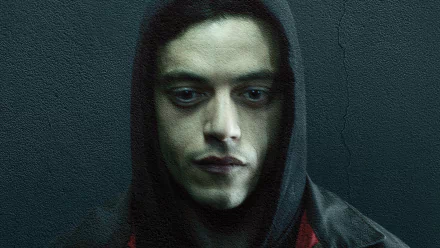 HD PC wallpaper: close-up of a hooded, brooding man against a textured teal wall — moody portrait from the TV show Mr. Robot.