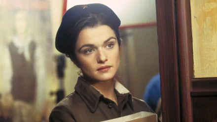 HD PC desktop wallpaper: scene from the movie Enemy At The Gates — close-up of a woman in wartime uniform and beret, holding papers, thoughtful expression in a dim corridor.