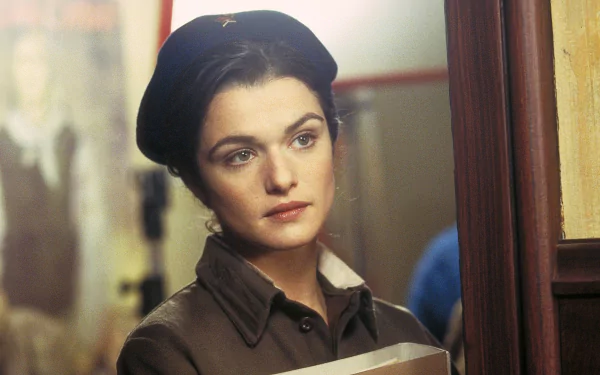 HD PC desktop wallpaper: scene from the movie Enemy At The Gates — close-up of a woman in wartime uniform and beret, holding papers, thoughtful expression in a dim corridor.