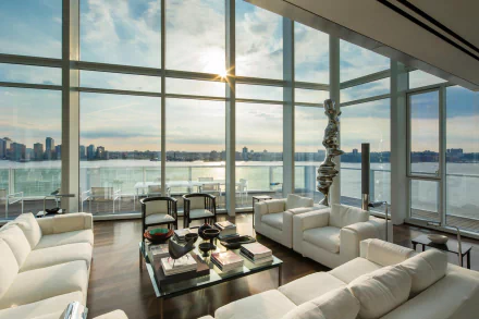 HD PC desktop wallpaper background: white penthouse living room with man-made modern furnishings, floor-to-ceiling windows framing New York skyline and river at sunset.