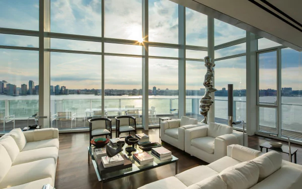 HD PC desktop wallpaper background: white penthouse living room with man-made modern furnishings, floor-to-ceiling windows framing New York skyline and river at sunset.