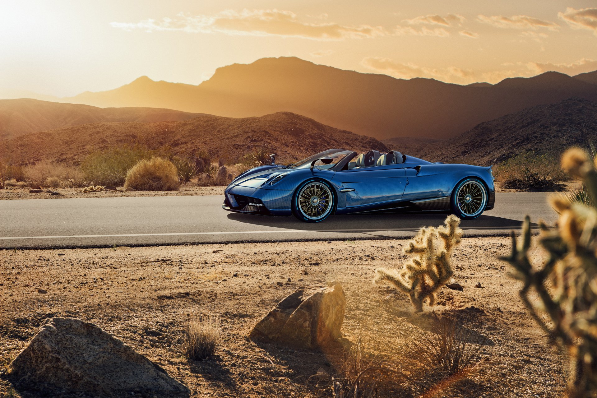 Blue Pagani Huayra supercar on a desert road at sunset, showcased as a high-definition PC desktop wallpaper and background.