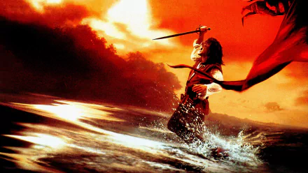 HD PC desktop wallpaper from the movie 1492: Conquest of Paradise — lone figure wading through surf, sword raised heroically against a fiery orange sky.