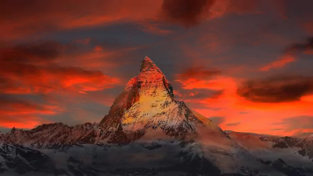 Stunning sunset view of the Matterhorn peak in Italy, with dramatic clouds and vibrant colors illuminating the mountain cliff. HD nature wallpaper and background.