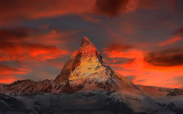 Stunning sunset view of the Matterhorn peak in Italy, with dramatic clouds and vibrant colors illuminating the mountain cliff. HD nature wallpaper and background.