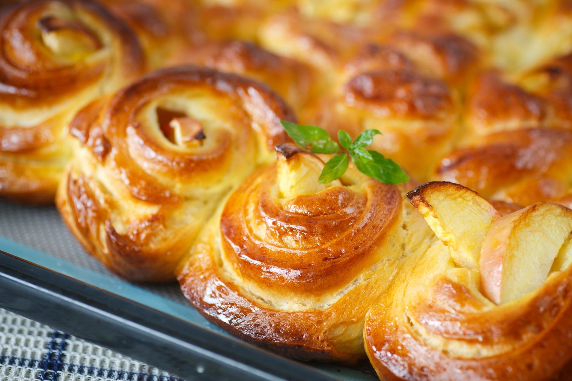 Close-up of golden, spiral pastries with a small mint garnish, displayed as a vibrant HD PC desktop wallpaper featuring delicious dessert food.